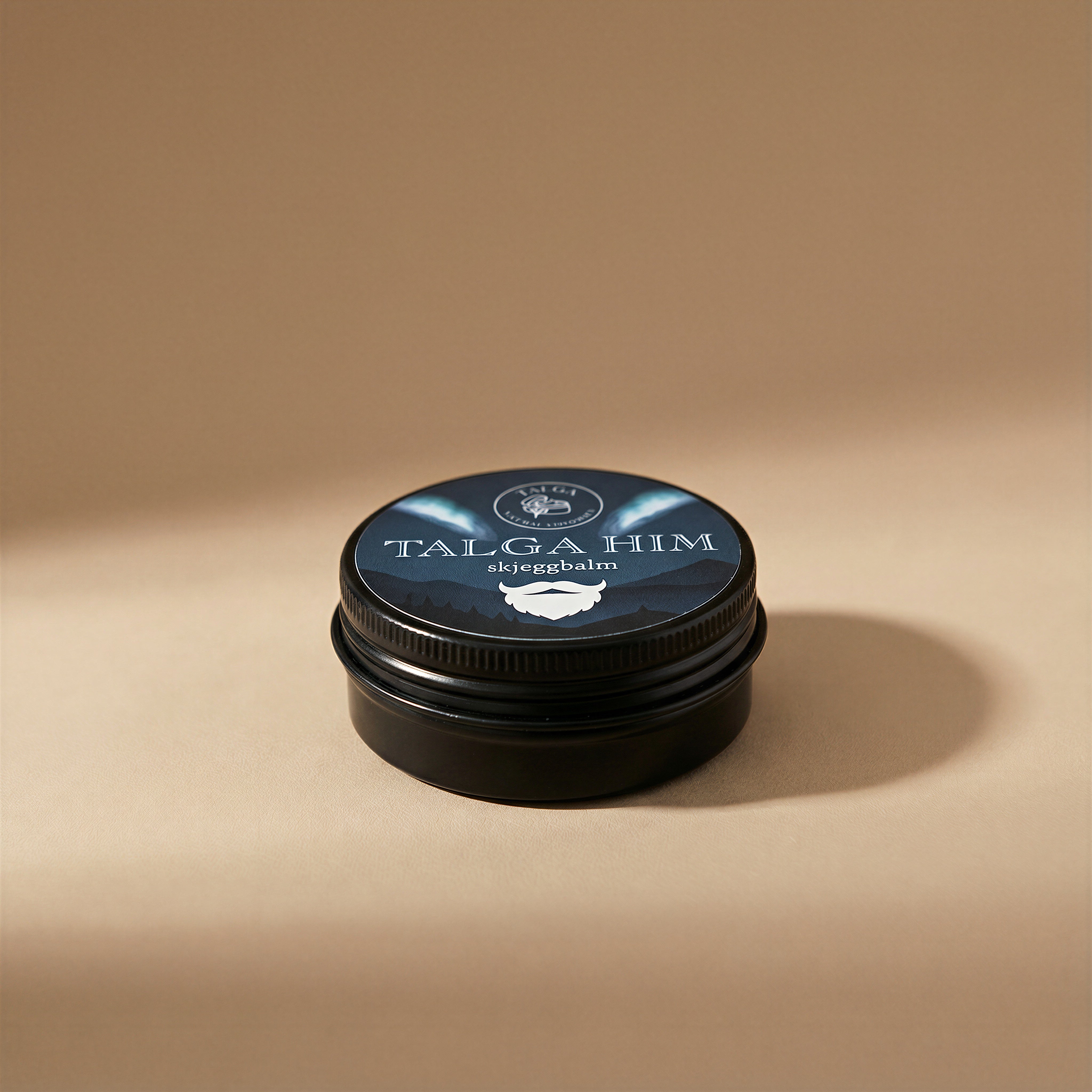 Talga Him beard balm in a black tin with a screw lid on a beige background.