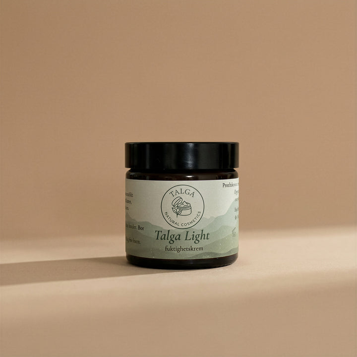 Talga Light moisturizing cream in an amber glass jar with a black lid on a beige background.
