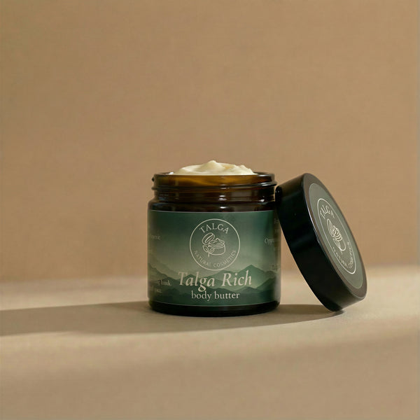 Talga Rich body butter in an amber glass jar with a black lid next to it on a beige background.